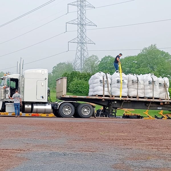 Unstrapping palletized Silt Socks from a semi truck flatbed.