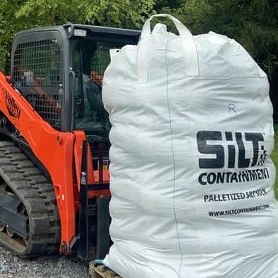 Orange skidsteer with a pallet of Silt Socks on the pallet forks.